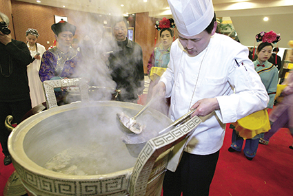 2005年3月20日，杭州，一位大厨正在从一只直径达0.8米的瓷鼎里盛装炖了10多个小时的蛇龟汤