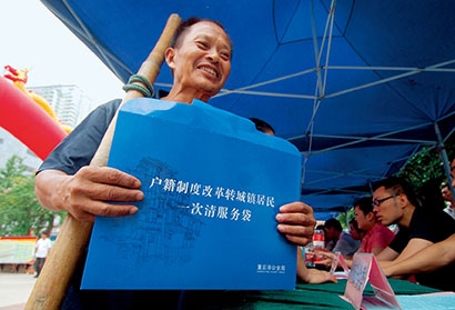 2010年8月15日，重庆市江北区观音桥步行街，一名外来务工人员在咨询点拿取户籍制度改革的相关资料。