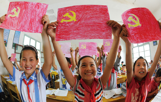 2011年6月15日，在安徽省亳州市谯城区汤陵办事处实验小学，留守儿童正在展示自己绘制的党旗。
