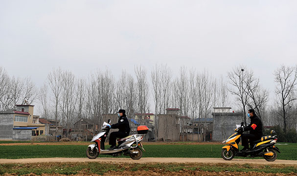 2月7日，唐河县公安局派驻郭滩镇前湾村驻村第一书记方显（左）与工作人员骑着电瓶车在村里宣传防疫知识。