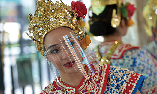 4．从5月3日起，泰国政府允许部分公园、餐馆、杂货店等公共和商业场所重新开放。图为5月4日，佩戴防护面罩的舞者在泰国曼谷四面佛表演舞蹈。