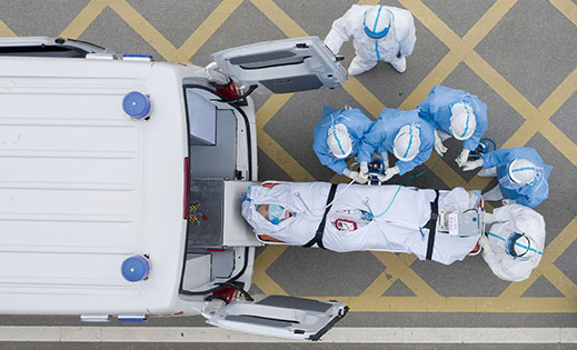 3月6日，在华中科技大学附属同济医院中法新城院区，医护人员护送一名刚做完CT检查的新冠肺炎重症患者上负压救护车。