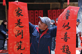 在杭州临安区天目山镇交口村，一名村民拿着刚写好的春联喜笑颜开。